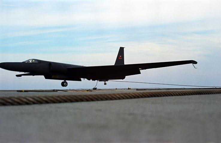 A U-2 aircraft just before landing on the tarmac on a blue sky day.