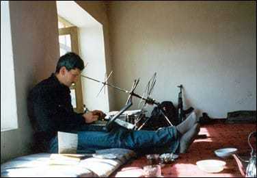An image of Johnny Span sitting with his back against the wall, typing on a laptop keyboard.