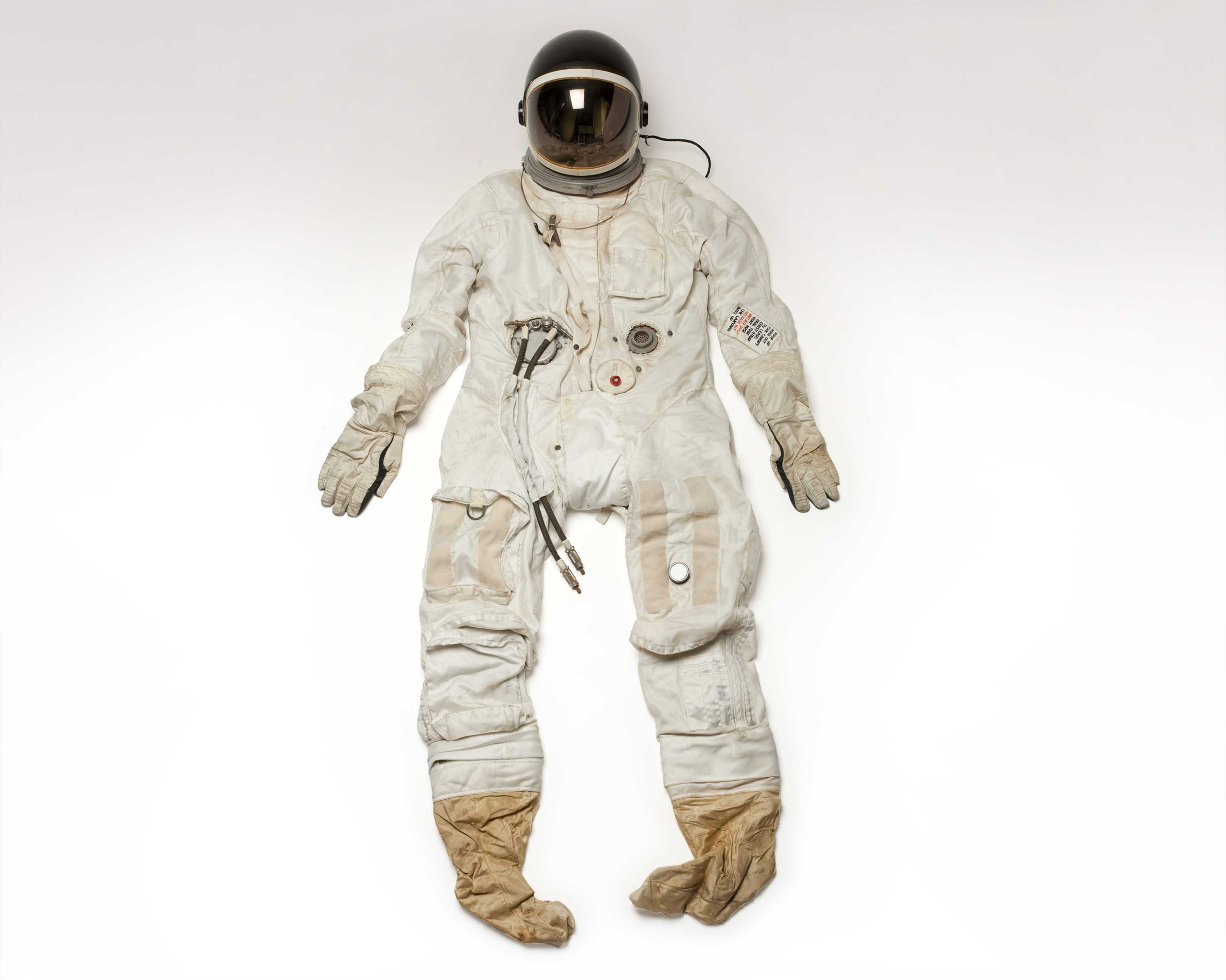 A white pressure suit in a standing position with yellow boots and a black helmet