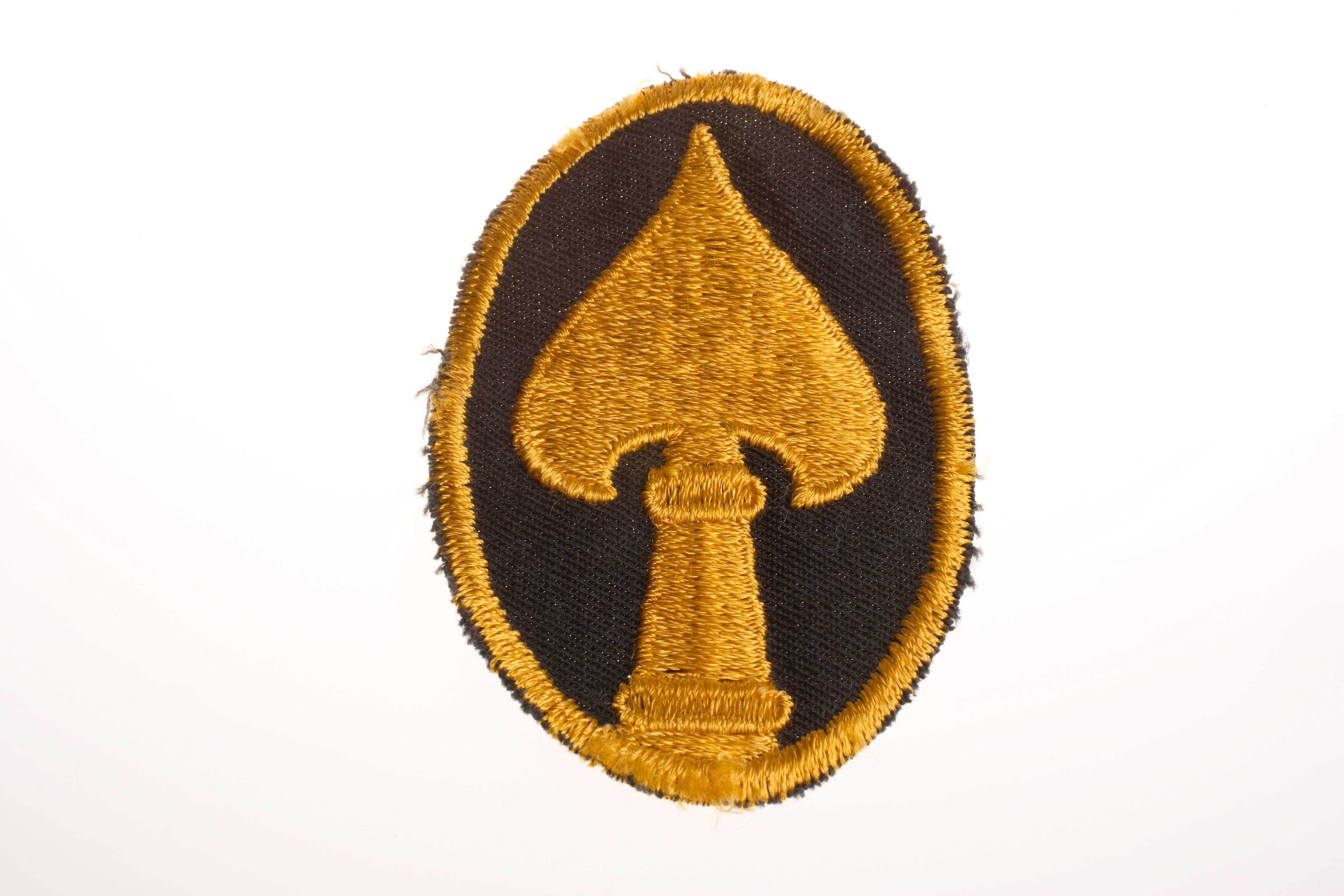 A patch with the OSS insignia, a gold tip of a spear with a black background