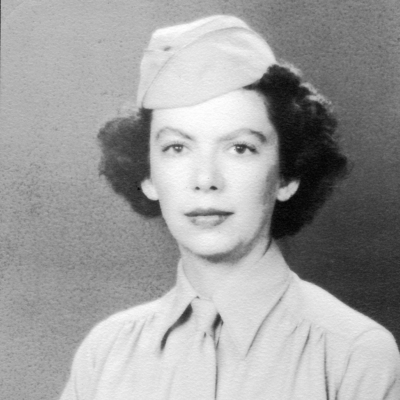 A black and white portrait photograph of Elizabeth wearing an Army Recruiting hat with a shirt and tie.