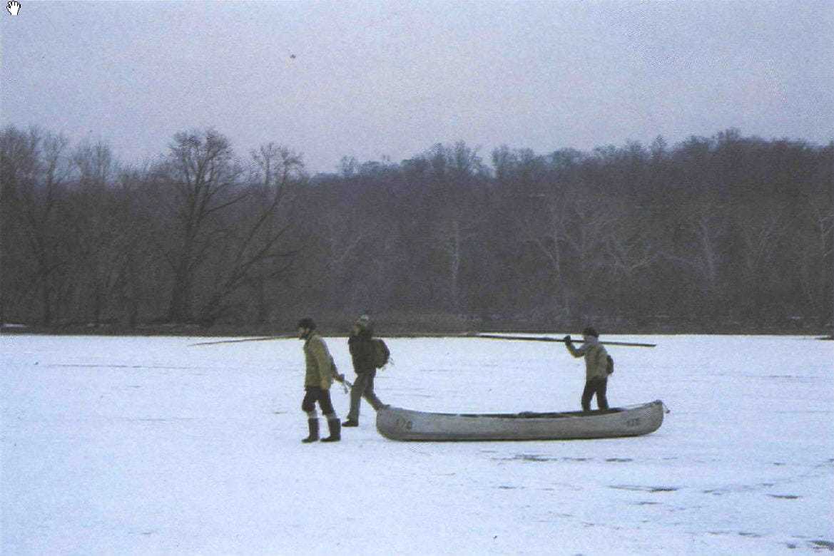 Three men dragging a canoe in the snow.