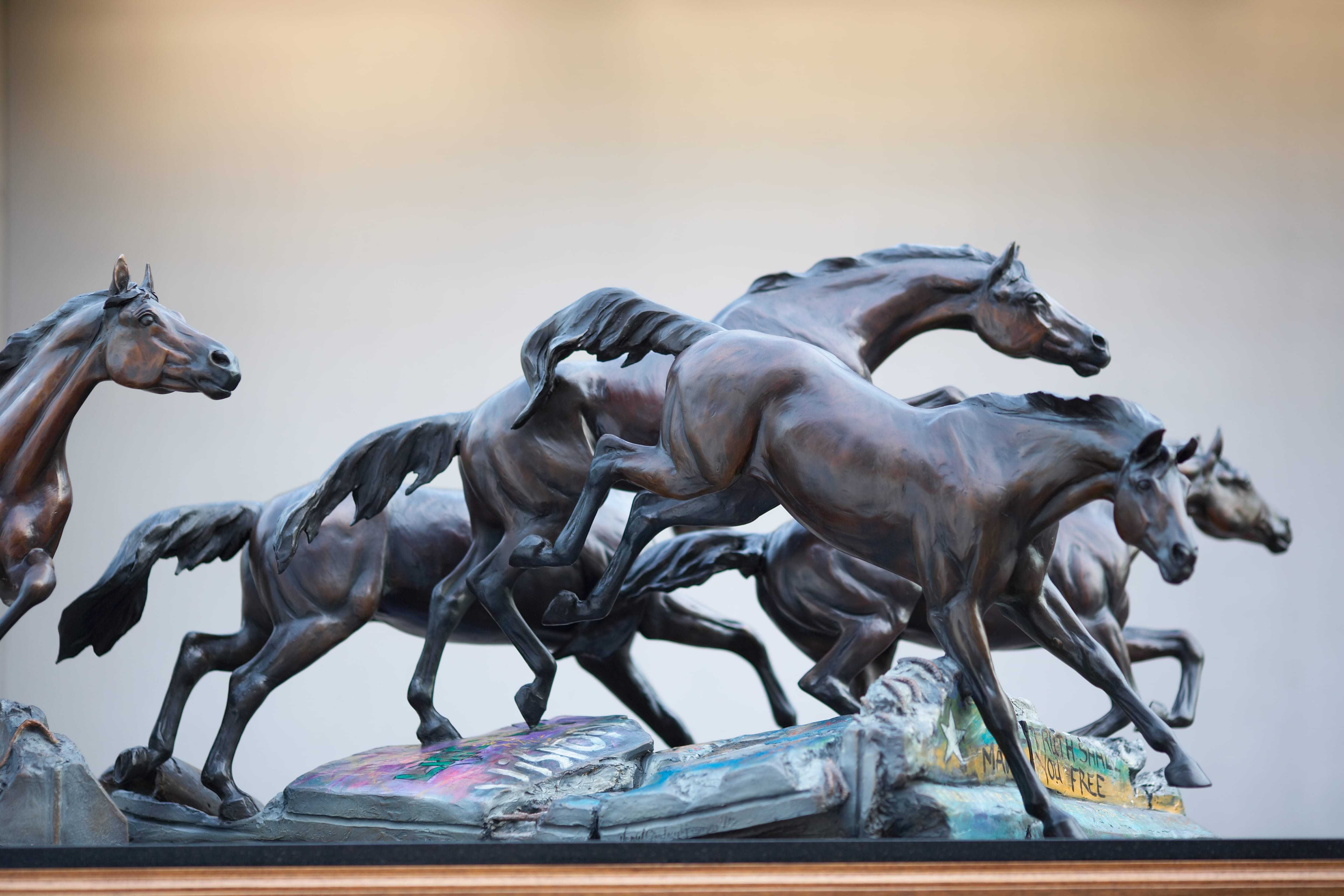 A sculpture of five horses leaping over the ruins of the Berlin Wall