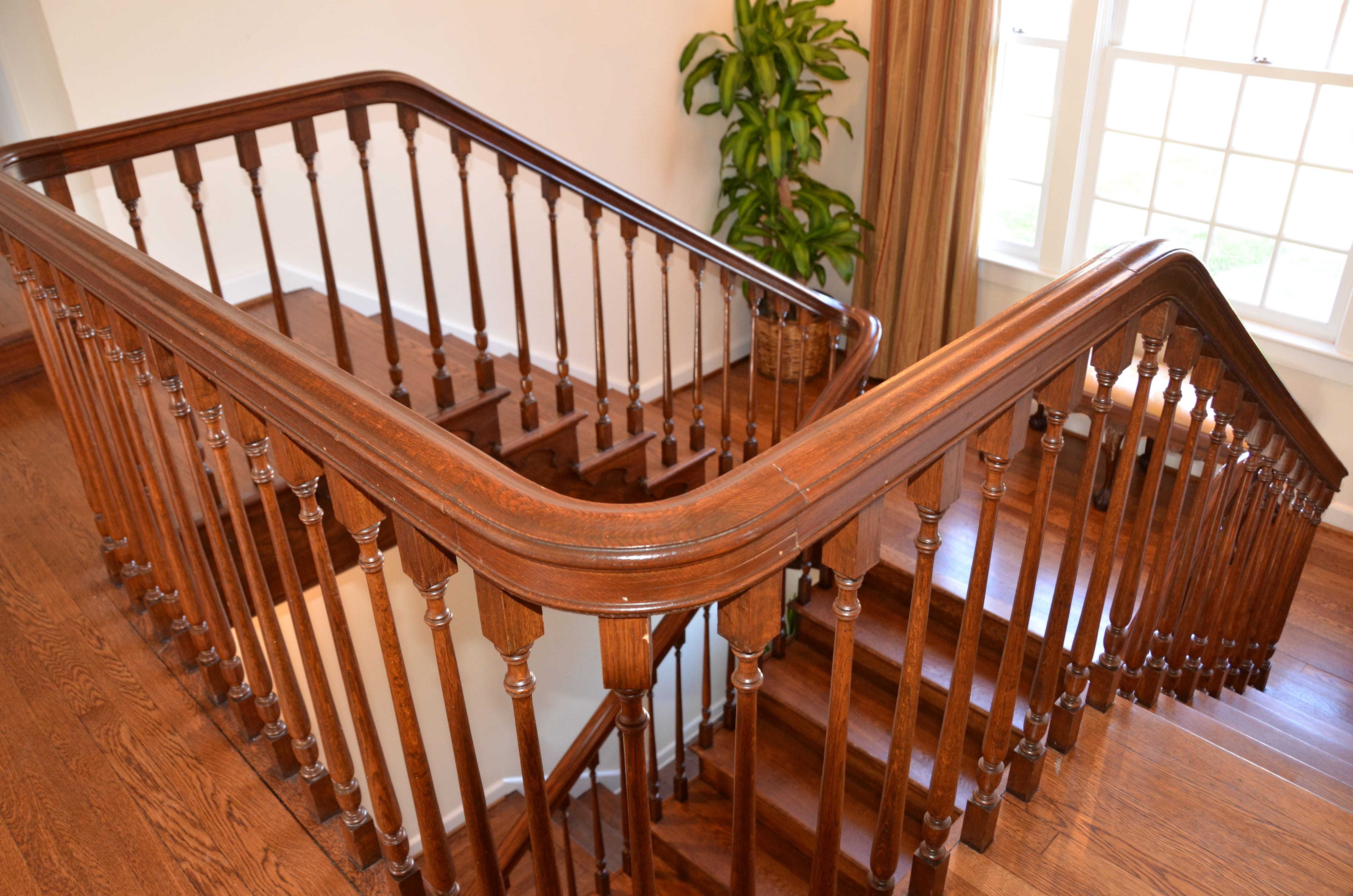 A shot from the second floor looking down at the wooden staircase and its wrap around bannister.