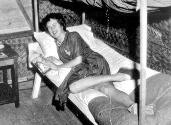 A black and white image of Julia laying on the bottom bunk of a bunk bed, smiling at the camera.