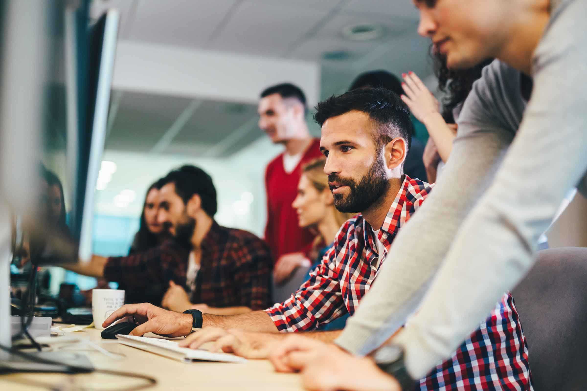 A group of young professionals in business casual clothes working on several computers.