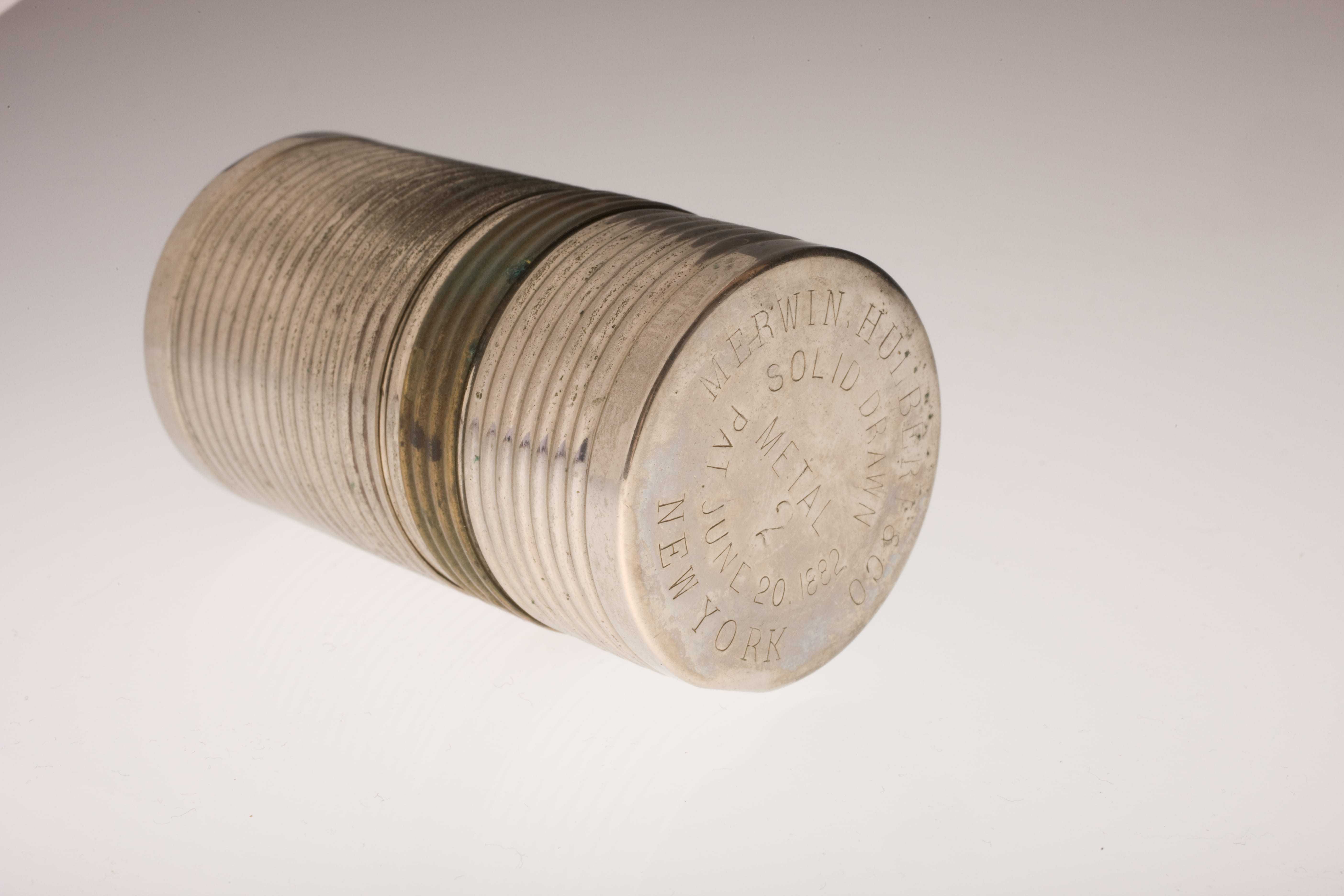 A cylindrical metal case with manufacturing information engraved on the end