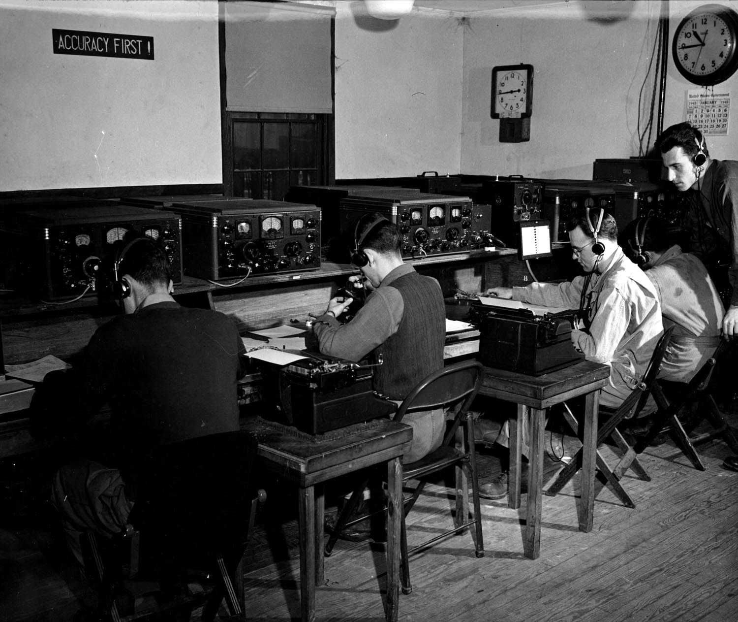 black and white 1940s image of young men sitting at tables decoding secret messages