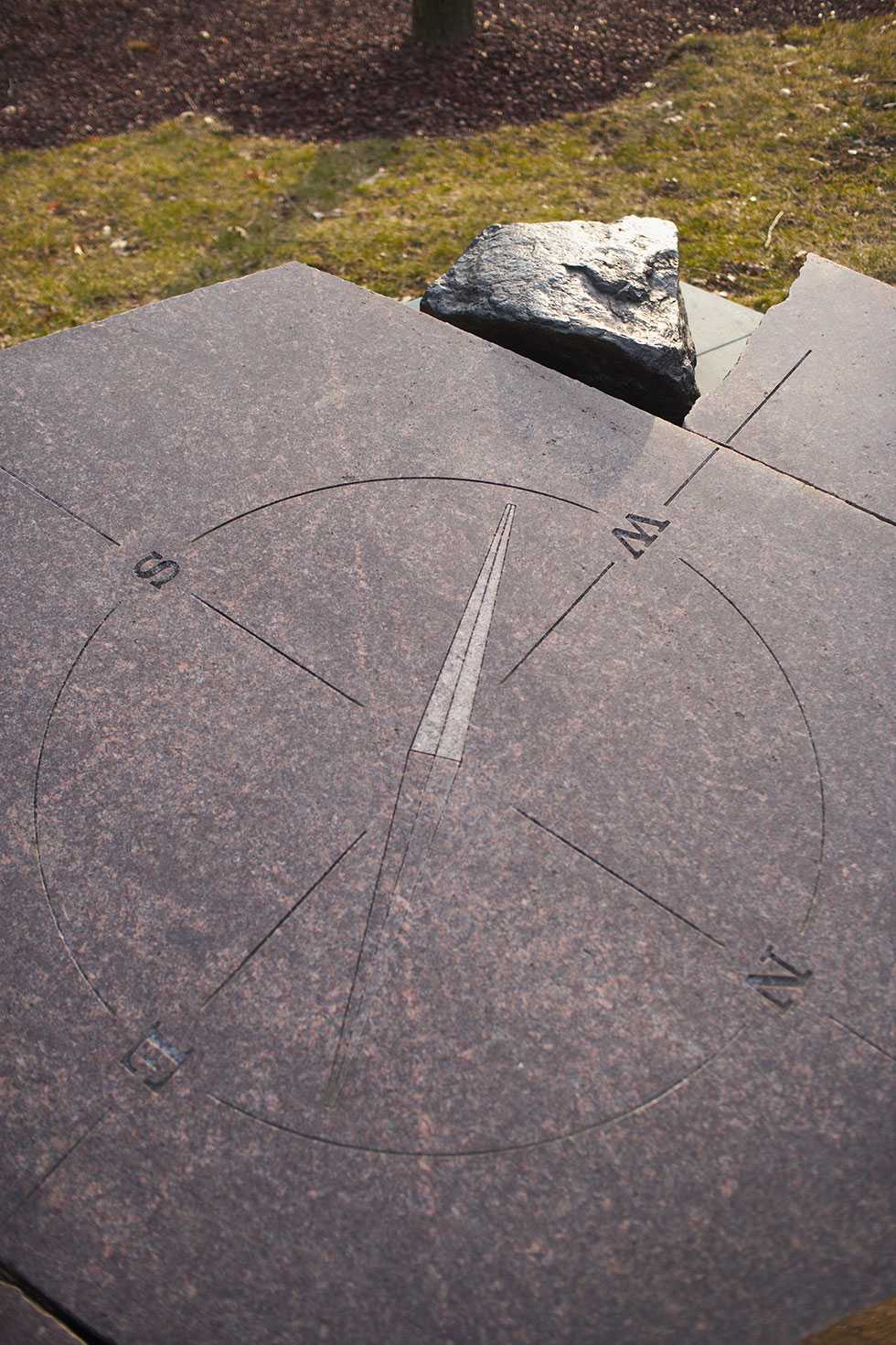 A compass pointing Southwest, inscribed on glossy stone on the ground.