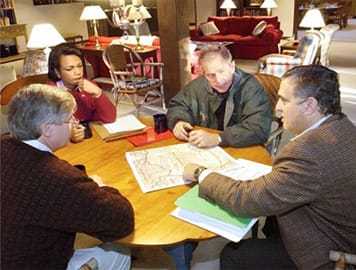 President George W. Bush with three senior officials sitting around a table looking at a map at Camp David.