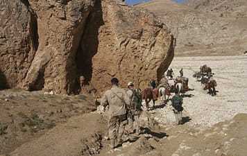 US troops traveling through a desert on foot and on horse.