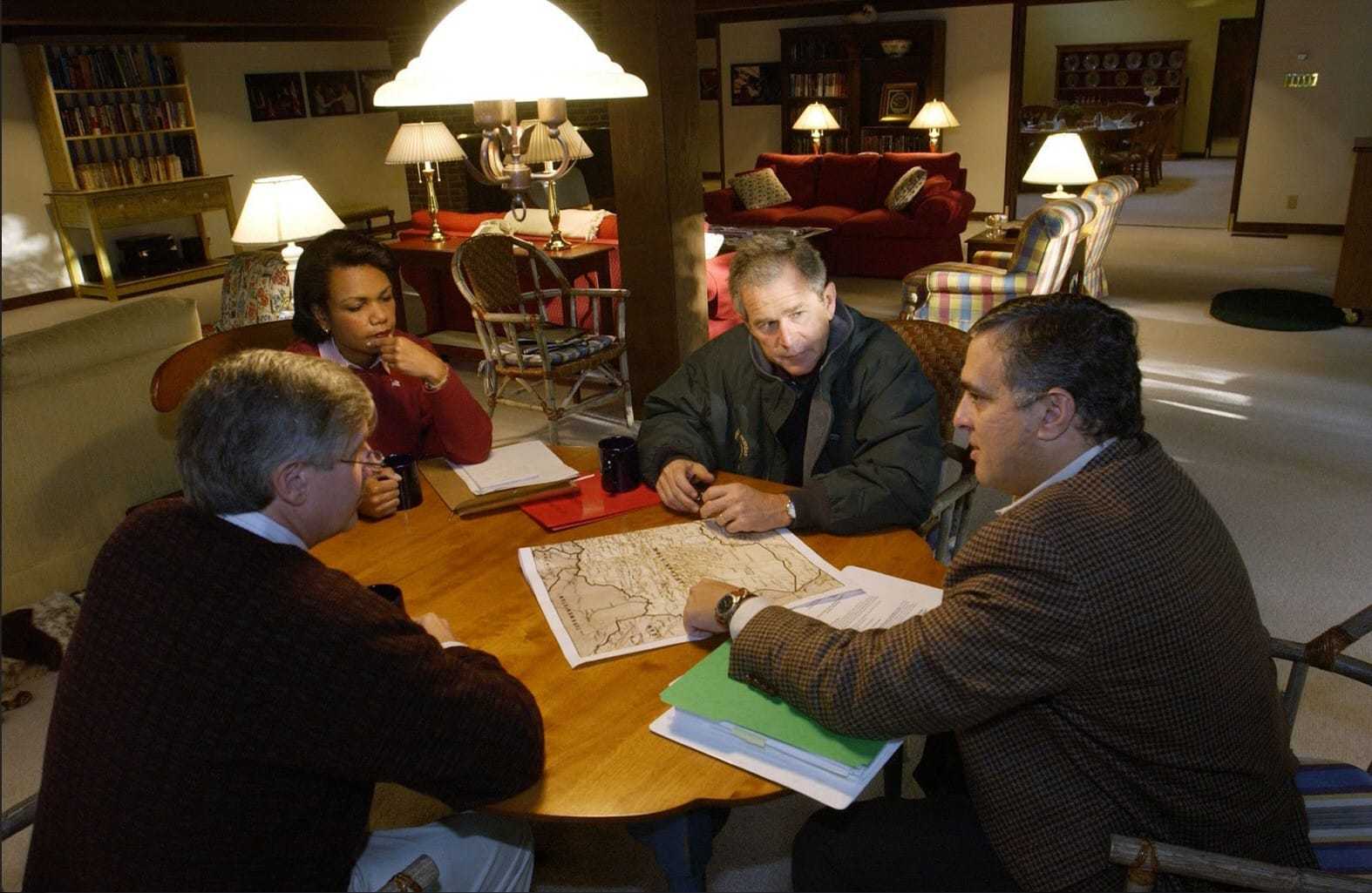 President George W. Bush with three senior officials sitting around a table looking at a map at Camp David.