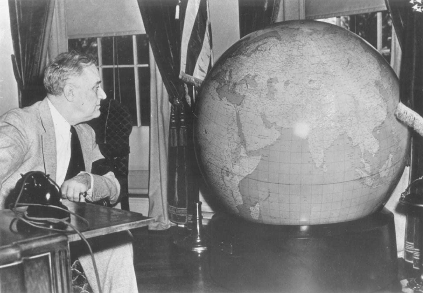 President Roosevelt looking at a large globe.