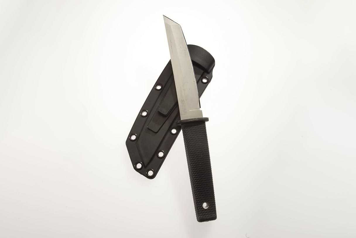 A knife with a black handle resting on top of a matching blade cover