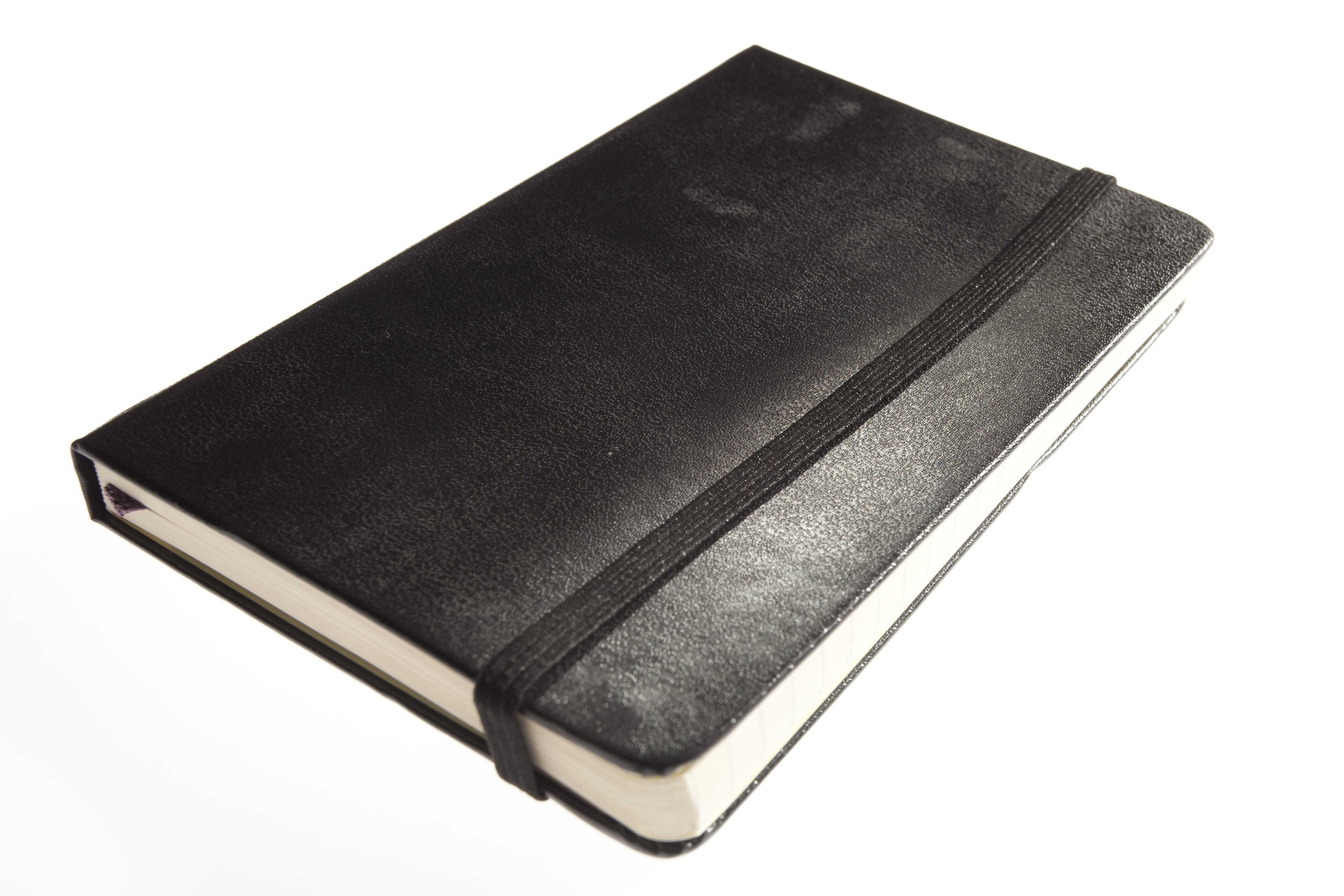 A black moleskin notebook held closed by an elastic band