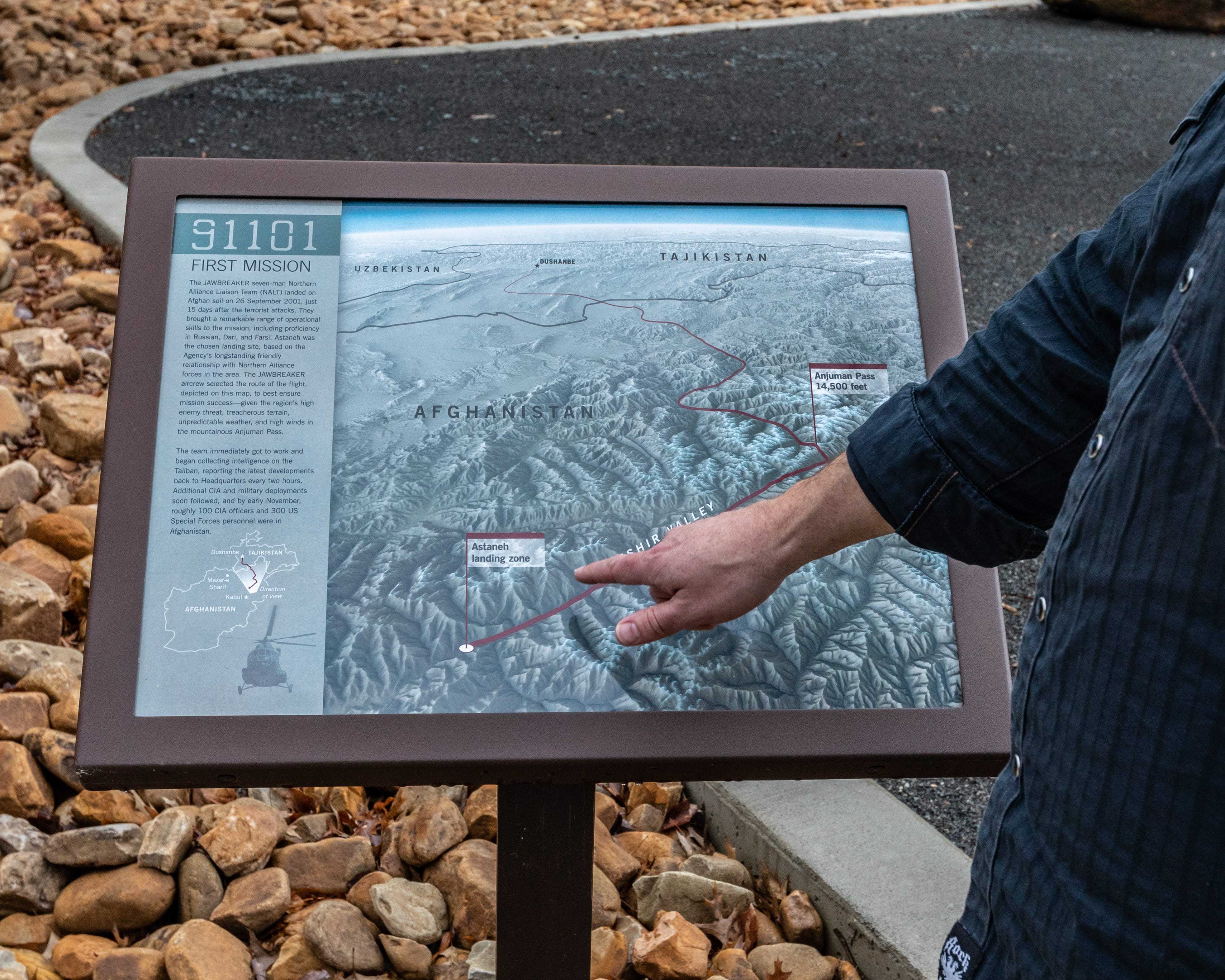 A hand pointing to a map on an outdoor sign.