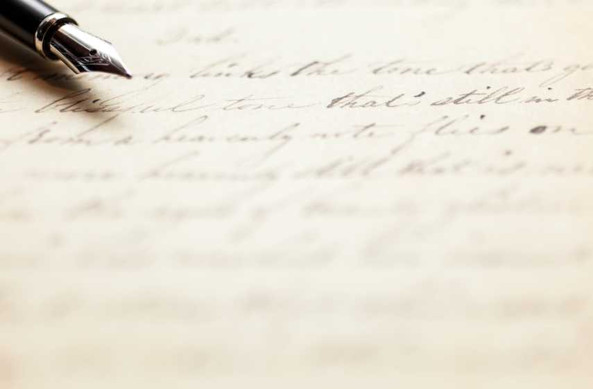 A blurred photograph of calligraphic handwriting with a pen in the upper left corner.