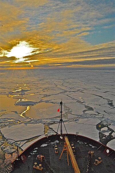 The early morning sun bursts through clouds over the Arctic Ocean in this view taken from atop the bridge over the bow of the USGC Healy. Photo courtesy of the US Geologic Survey/ Jonathan Wynn.