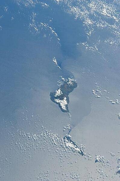 Grande Comore appears in the center of this view with Moheli (mostly cloud covered) toward the bottom. The silvery surface of the Mozambique Channel is due to sun glint. Photo courtesy of NASA.