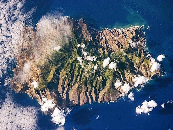 Saint Helena&apos;s rugged topography of sharp peaks and deep ravines - evident in this photograph from the International Space Station - is the result of erosion of the volcanic rocks that make up the island. A climatic gradient related to elevation is also evident - the higher, wetter central portion of the island is covered with green vegetation, whereas the lower coastal areas are drier and hotter with little vegetation cover. Image courtesy of NASA.