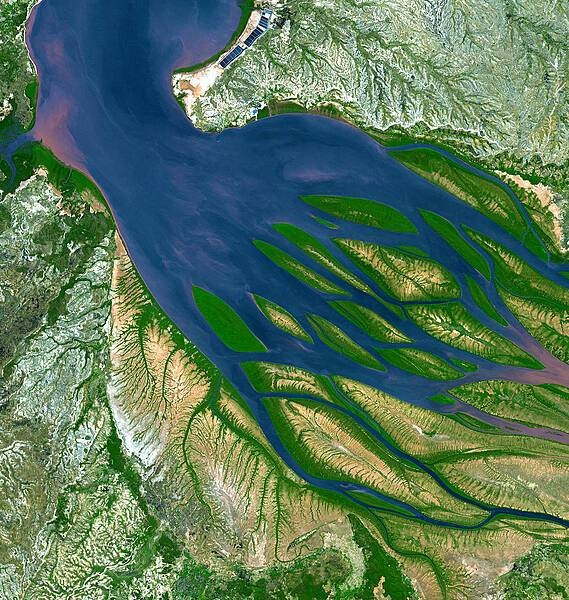 On the northwestern coast of Madagascar, the salty waters of the Mozambique Channel (top, north) penetrate inland to join with the freshwater outflow of the Betsiboka River (right, east), forming Bombetoka Bay. Numerous islands and sandbars have formed in the estuary from the large amount of sediment carried in by the Betsiboka River and have been shaped by the flow of the river and the push and pull of tides. Image courtesy of NASA.