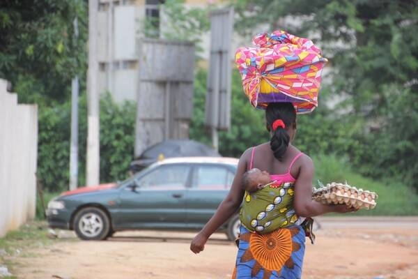 A woman carrying eggs and a baby.
Côte d'Ivoire is a juxtaposition of urban and rural conditions. Its cities, particularly Abidjan, are full of modern office buildings, condominiums, European-style boutiques, and trendy restaurants. They stand in sharp contrast to the country's many villages - accessed mainly by dirt roads - whose architecture is comprised of huts and simple abodes. While the cities are described as crowded urban enclaves with traffic and a dichotomy of rich and poor residents, the villages are filled with farmers tending their fields, native dress, homemade pottery, and traditional tribal rituals.