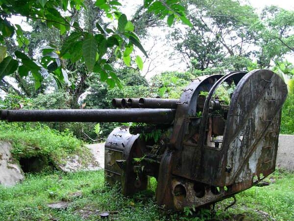 The remains of a Japanese dual mount Type 89 12.7 cm (5") anti-aircraft gun located on Sohkes Mountain Ridge overlooking the harbor on Pohnpei Island. As the largest island in the Caroline Islands with an excellent harbor and two airfields, Pohnpei was heavily defended by the Japanese during World War II. A similar anti-aircraft gun is located nearby along with a 6" coast artillery gun. Although subjected to repeated Allied air attacks, the island was bypassed during the Allied campaign in the Central Pacific and the island remained in Japanese hands until the end of World War II. Photo courtesy of NOAA / Lieutenant Commander Matthew Wingate.