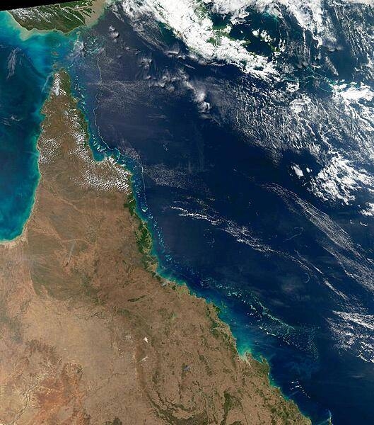 This view of the Queensland coast of northeast Australia taken by the Aqua satellite vividly shows the many offshore reefs that together form the Great Barrier Reef. The various white specks in the deeper blue waters of the Coral Sea to the east are some of the reefs, cays, and islets that make up the Coral Sea Islands. Image courtesy of NASA.