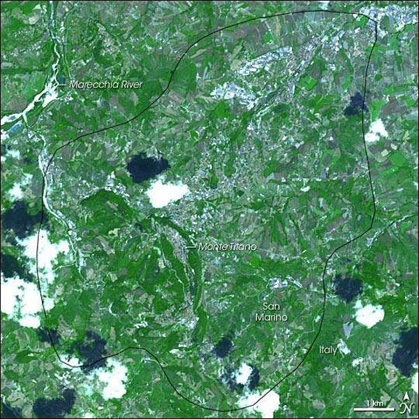 With an area of just 61 sq km (23.5 sq mi), San Marino is the third-smallest country in Europe, behind Monaco and the Holy See. Located in the northern part of the Italian Peninsula, near the Adriatic Sea, this tiny nation is surrounded by Italy.This satellite picture of San Marino shows a combination of vegetation (bright green); and buildings, pavement, and bare rock (blue-gray to white). Purplish-gray polygons are probably fallow agricultural land. Overhead, fluffy white clouds cast their charcoal-colored shadows over the land surface. The Apennine Mountains give the region a rough terrain, and the limestone Monte Titano dominates the area, with a fort perched on each of the mountain's three summits. According to legend, San Marino is the world's oldest surviving republic, dating back to 301. The original city sits atop Monte Titano. Today, however, development has spread throughout the republic, evidenced by the many areas of blue-gray and the meandering roads. Tourism has brought prosperity to this small republic, but historically, its rugged terrain and lack of wealth may have helped it escape the unwanted attention of potential invaders. Image courtesy of NASA.