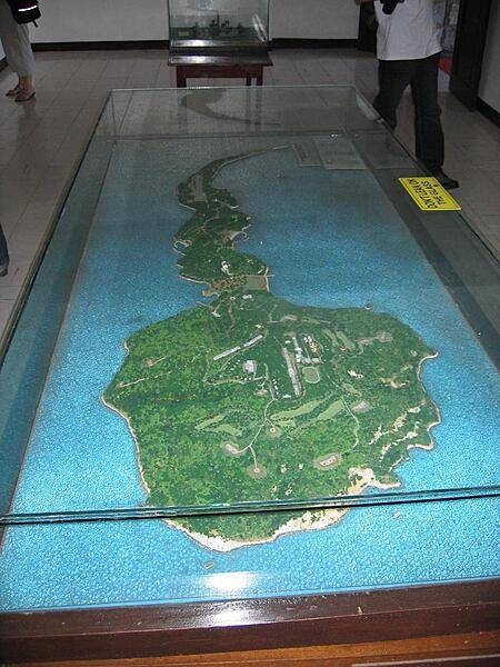 A scale relief map of the tadpole-shaped island of Corregidor. The island is 6 km (4 mi) long and 2.4 km (1.5 mi) at its widest point, with an area of 5 sq km (2 sq mi) and a highest elevation of 121 m (397 ft). The island, part of an ancient volcanic caldera, divides the entrance to Manila Bay into two main passages, North Channel and South Channel. Construction of fortifications on Corregidor began as early as 1904 as part of the Manila harbor defenses and were primarily designed to meet a seaborne attack.