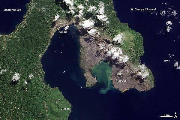 Volcanic cones and settlements mingle along the margins of the Rabaul Caldera on the northeastern tip of Papua New Guinea&apos;s New Britain Island. Shaped like a giant cauldron, the caldera is the remaining rim of an ancient volcano. Small volcanic cones, some of which are still active, sit on the rim. Spanning roughly 8 by 14 km (5 by 9 mi), the caldera is flooded by Blanche Bay. The largely submerged caldera long formed a natural harbor for what had been New Britain&apos;s largest city, but a major eruption forced the evacuation of Rabaul City in 1994. Although the city ceased to bustle with activity, at least one volcanic cone remained active for years afterward.
The landscape in this satellite image appears as a mixture of vegetated and bare ground. Vegetation almost completely coats the western side of Rabaul Caldera. Volcanic cones line the northeastern margin of the caldera, and around these cones, the land is mostly rocky and barren.
Tavurvur, near the southern end of the exposed caldera rim, was one of the volcanoes to erupt explosively in 1994. The other was Vulcan, on the western side of the caldera. While vegetation has revived on the slopes of Vulcan, rocks predominate at Tavurvur, evidence of more recent eruptive activity.
Remnants of settlements linger along the caldera&apos;s northwestern margin and on a promontory near the caldera&apos;s center. Prior to the explosive eruption in 1994, the city of Rabaul had been the provincial capital of East New Britain. After the eruption, the capital was moved to the coastal city of Kokopo, some 20 km (12 mi) to the southeast. Photo courtesy of NASA.