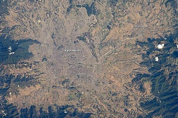 The capital and largest city of Nepal, Kathmandu, occupies much of the valley located near the center of the country. Nepal is home to much of the Himalaya mountain range between Tibet (China) to the north and India to the south. Geological and fossil evidence indicates that the Kathmandu Valley was covered by a large lake between approximately 2.8 million and 10,000 years ago. Paleo-Kathmandu Lake is thought to have drained in phases due to the drying of the regional climate; continuing mountain building-tectonic uplift and faulting-in the region; and the formation of an integrated drainage system, as river channels cut through previous rock ridge dams.
The green, vegetated slopes that ring the Kathmandu metro area (light gray, image center) include both forest reserves and national parks. The metropolitan area is relatively flat compared to the surrounding mountains. Tribhuvan International Airport, near the eastern margin of the city, is the only international airport in Nepal. 
Archeological evidence suggests that the human development of Kathmandu, together with the nearby &quot;sister cities&quot; of Lalitpur and Bhaktapur, began almost 2,000 years ago. Today, the three cities form the governmental, cultural, and-as a main access point to the Himalayas for tourism-economic center of the country. Photo courtesy of NASA.