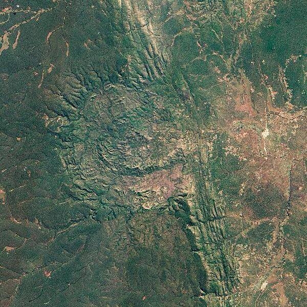 The Luizi Structure, located in southeastern Congo, is a crater covered by grasses up to a meter (3 ft) high. The crater seen in this satellite image has about a 17 km (11 mi) diameter, with an intermittent ring about 5.2 km (3.2 mi) across, and a smaller, center ring about 2 km (1.2 mi) across. Around the perimeter of the crater, a rim rises approximately 300 to 350 m (980 to 1,150 ft) above the interior. In short, Luizi is a well-preserved, moderately sized, complex crater. Exactly when Luizi formed is difficult to answer. Researchers estimate that nearby rocks are 575 million years old - more than 300 million years older than the first dinosaurs. But besides knowing that the impact cannot be older than the rock layers it disrupted, geologists still cannot say when the impact occurred. Photo courtesy of NASA.