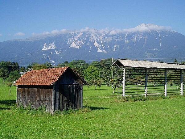 A farm field in Slovenia near Lake Bled, with the Julian Alps in the background. The structure on the right is a rack for drying hay, a design unique to Slovenia.