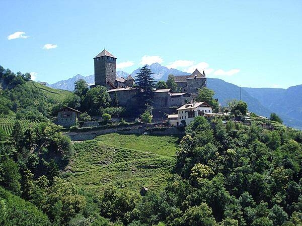 A view of Tyrol Castle and its surrounding rugged mountains.