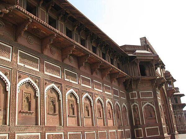 Agra Fort, also known as the Red Fort of Agra, represents the opulence and power of the Mughal Empire of the 16th to the early 18th century. The fortress, located on the right bank of the Yamuna River, is built of red sandstone and covers a length of 2.5 km (1.6 mi). It is surrounded by a moat, which encloses several palaces, towers, and mosques. Shown here is the Jahangiri Mahal, the most prominent building at Agra Fort. The entire complex was inscribed onto the UNESCO World Heritage List in 1983.