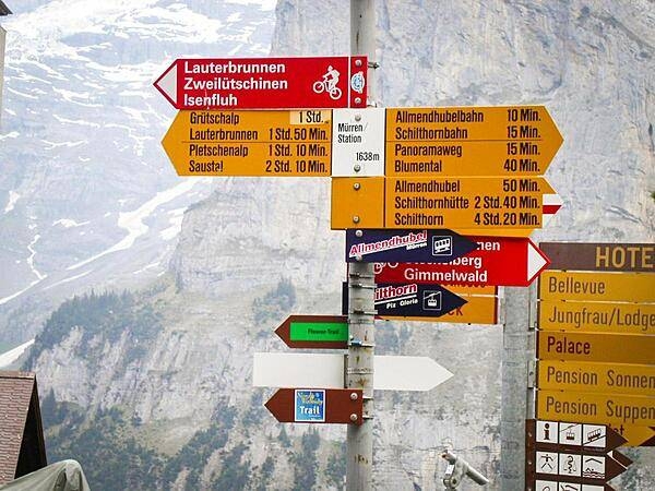 Way signs in Murren, a traditional mountain village in Bernese Oberland, unreachable by public road. The village features a view of the three towering mountains: Eiger, Monch, and Jungfrau. At an elevation of 1,650 m (5,413 ft), access to the village is via four cable cars known as Luftseilbahn-Stechelberg-Murren-Schilthorn (LSMS), which also provide access to the summit of Schilthorn, the location of a rotating restaurant with spectacular views.
