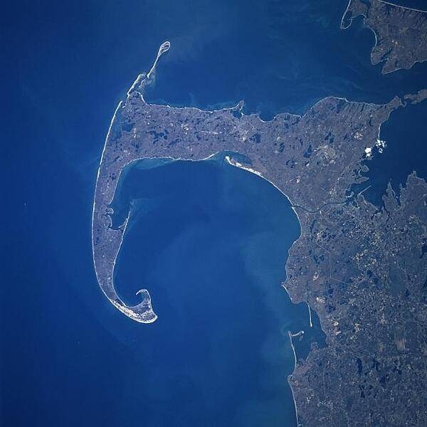 Cape Cod and Cape Cod Bay (visible at the center of the image) can be seen in this generally south-looking view. Cape Cod is a narrow peninsula, glacial in origin, that is constantly changing as winds and water move sand along the shoreline. Cape Cod extends 105 km (65 mi) east and north into the Atlantic Ocean. A portion of Martha&apos;s Vineyard may be seen in the upper right corner of the image. Photo courtesy of NASA.