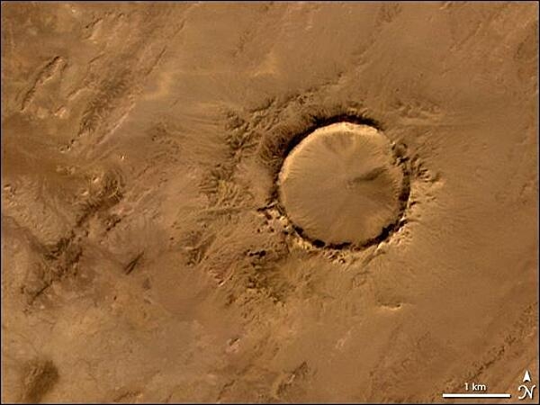 The Tenoumer crater, a nearly perfect circle in the Sahara Desert, is 1.9 km (1.2 mi) wide and sports a rim 100 m (330 ft) high. Close examination of the structure has revealed that the crater's hardened "lava" was rock that melted from a meteorite impact. Photo courtesy of NASA.