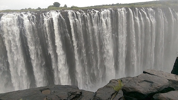 Victoria Falls is located on the border of Zambia and Zimbabwe. During flood season (February to April), the falls form the greatest sheet of falling water on earth. Victoria Falls is 1.7 km (1.1 mi) wide and 108 m (360 ft) high and is known locally as Mosi-oa-Tunya (The Smoke that Thunders).
