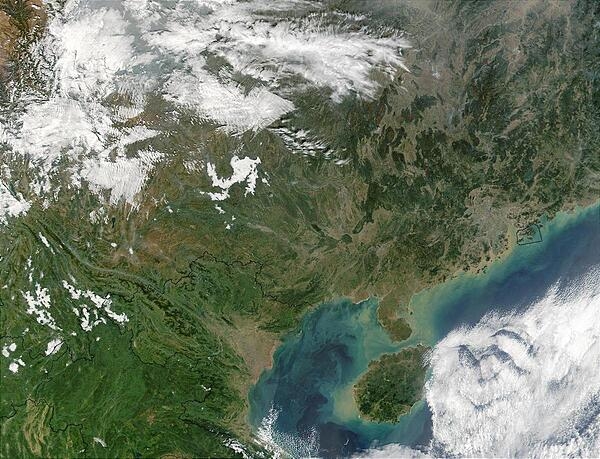A view of Southern China and the Gulf of Tonkin. At the center-right of the image, circled in a black outline, is the island of Hong Kong. Hong Kong sits on the South China Sea, which is mostly under cloud cover in this image. West of the South China Sea is the island of Hainan, seen at bottom-center, which separates the sea from the Gulf of Tonkin to the west. In this image, the Gulf of Tonkin is saturated with what seems to be a mixture of sediment and phytoplankton. Photo courtesy of NASA.