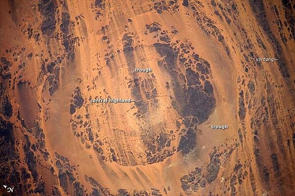 Aorounga Impact Crater, located in the Sahara Desert of north-central Chad, is one of the best-preserved impact structures in the world. The crater is thought to be about 345-370 million years old, based on the age of the sedimentary rocks deformed by the impact. Radar data suggests that Aorounga is one of a set of three craters formed by the same impact event. The other two suggested impact structures are buried by sand deposits. Image courtesy of NASA.