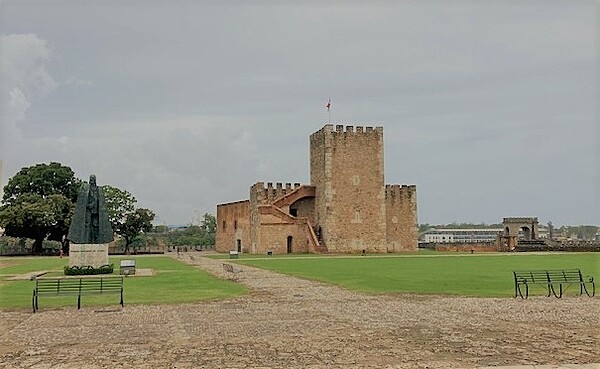 The Ozama Fortress is recognized by UNESCO as the oldest military construction of European origin in the Americas. It was built between 1502 and 1508 of coral stones, and is part of the Colonial City in Santo Domingo overlooking the Ozama River. An architectural structure of medieval style and design, the Tower of Homage stands in the center of the grounds. During the 16th century, the 18-meter-high tower was the tallest European-built construction of the Americas. The statue on the left depicts Gonzalo Fernández de Oviedo y Valdés, governor of the fortress from 1533 to 1557.