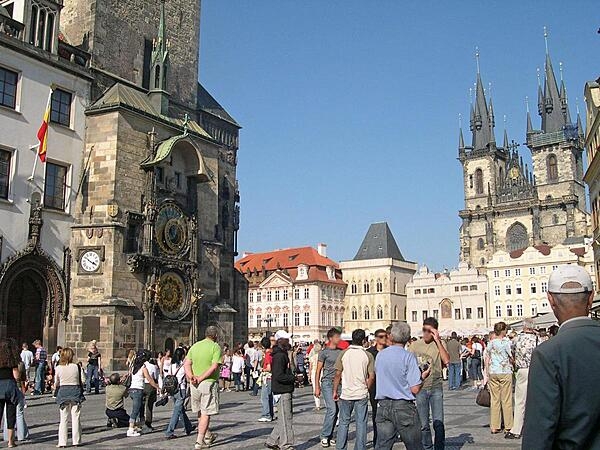 A view of a section of the Old Town Square in Prague. The medieval astronomical clock on the Old Town City Hall dates to 1410. In the background is Tyn Cathedral, one of the oldest churches in Prague, whose construction began in the 14th century.