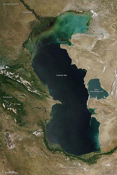 Measured by surface area, the Caspian Sea is the world&apos;s largest inland water body. It covers roughly 371,000 sq km (143,200 sq mi) and borders five countries. To the ancient Greeks and Persians, the lake&apos;s immense size suggested it was an ocean, hence its name. A large expanse of clear sky permitted this natural-color satellite image of the entire water body. The color of the Caspian Sea darkens from north to south, thanks to changes in depth and perhaps sediment and other runoff. The northern part of the lake is just 5 to 6 m (16 to 20 ft) deep. The southern end, however, plunges more than 1,000 m (3,300 ft). Just as the lake reaches a greater depth in the south, the nearby land reaches a greater height. The mountains of northern Iran line the southern end of the giant lake, and emerald green vegetation clings to those mountain slopes. In marked contrast to the mountains, sand seas line the southeastern and northern perimeters of the lake, and marshes occur along the lake shores in Azerbaijan to the west. Multiple rivers empty into the Caspian Sea, the Volga being the largest. Lacking an outlet, the Caspian Sea loses water only by evaporation, leading to the accumulation of salt. Although a lake, the Caspian is not a freshwater lake; the water delivered by the Volga River minimizes the lake&apos;s salt content at the northern end, but the Caspian grows more saline to the south. Kara-Bogaz-Gol is a saline inlet along the lake&apos;s eastern perimeter. Image courtesy of NASA.