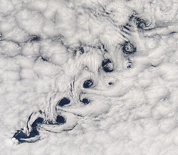 This image shows vortex shedding occurring as winds pass Heard Island (in the lower left) resulting in a Kármán vortex street - a repeating pattern of swirling vortices - in the clouds. Photo courtesy of NASA.