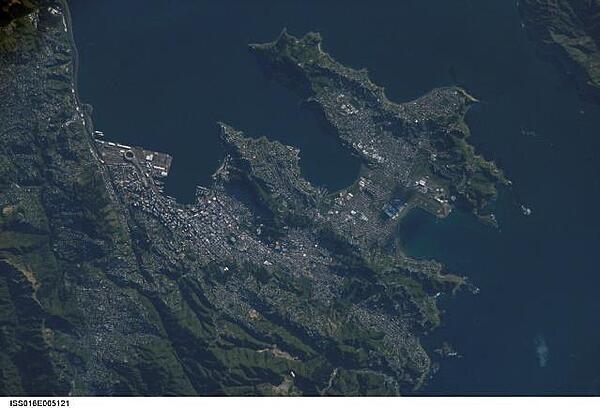 A view of New Zealand&apos;s capital of Wellington, located at the southwestern tip of North Island near the Cook Strait. The city is the second largest in New Zealand (after Auckland), and at 41 degrees south latitude, it is the southernmost capital city in the world. Five major geologic faults run through the Wellington municipality. Recognition of the potential seismic hazard in the metropolitan area has led to the adoption of building codes to maximize structural resistance to earthquake damage. Click on photo to increase resolution. Image courtesy of NASA.