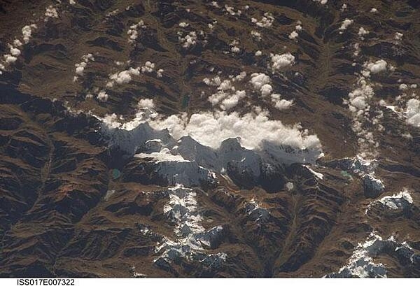 This view of the Peruvian Andes was taken looking east from the international space station flying off the Peruvian coast and shows Cordillera Huayhuash (pronounced Why-wash). Here clouds are banked up on the east side, snow covers all higher slopes and mountain peaks, and glaciers occupy lower slopes. This prominent but short mountain range (25 km or 15 mi in length) boasts twenty peaks of remarkable steepness and ridge sharpness. Although only 100 km (60 mi) from the coastline, six of the peaks reach above 6,000 m (more than 19,500 ft), the highest of which is Nevado Yerupaja, Peru&apos;s second highest peak, variously estimated as 6,617 and 6,635 m high. Generally considered the most spectacular peak in South America, Yerupaja is so steep that it has seldom been climbed. Photo courtesy of NASA.