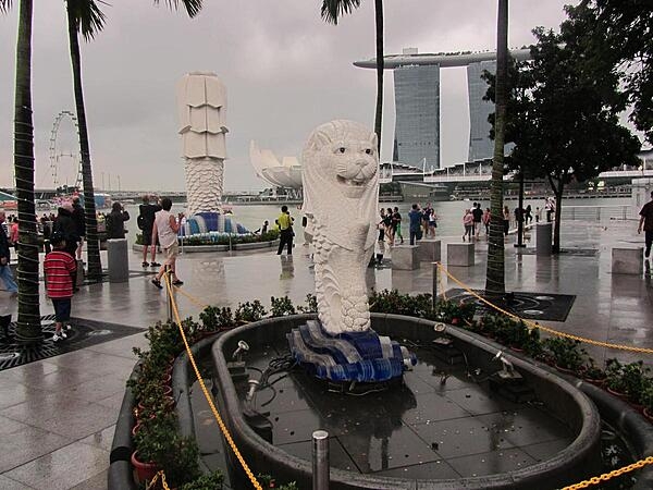 Smaller of the two Merlions (lion head and body of a fish) along the Singapore River. The word &quot;Sing&quot; comes from the Malay word for lion; thus the city is often called &quot;Lion City.&quot; In the background looms the back of the statue of the larger Merlion, the Marina Bay Sands Hotel built to resemble a ship on towers, and the lotus flower-shaped ArtScience Museum.