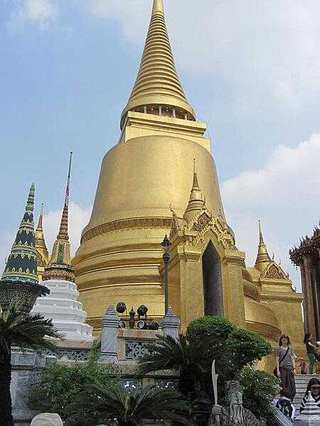 View inside the Grand Palace in Bangkok, Thailand, showing the golden Phra Siratana Chedi. A chedi, or stupa, is a mound-like reliquary containing Buddhist relics. The chedi is on the grounds of the Temple of the Emerald Buddha.